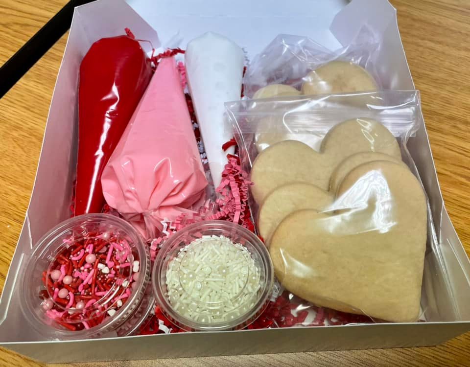 photo of kit with six gluten-free heart-shaped sugar cookies, three frosting tubes, red, pink and white, and two small containers of sprinkles