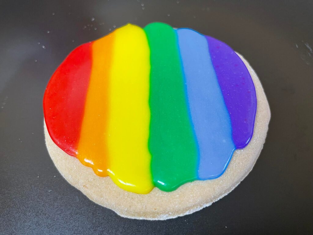 round gluten-free cutout sugar cookie frosted with rainbow colors
