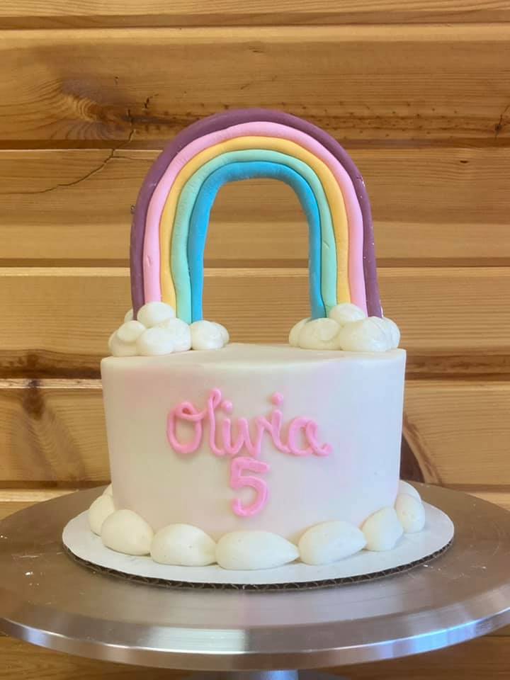 layer cake with with white frosting and a large rainbow on top.  Cake says Olivia age 5