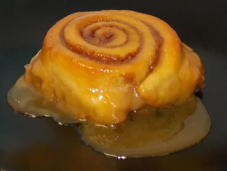 a photo of a gluten-free caramel sweet roll in a pool of caramel