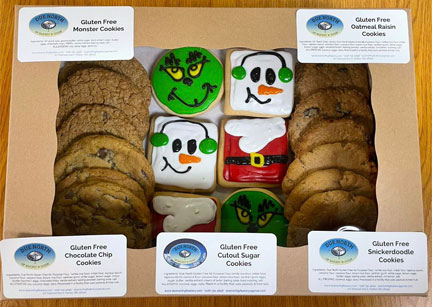 picture of box of cookies with gluten-free chocolate chip, monster, snickerdoodle & oatmeal raisin cookies with holiday cutout sugar cookies decorated as the grinch, snowmen and santa