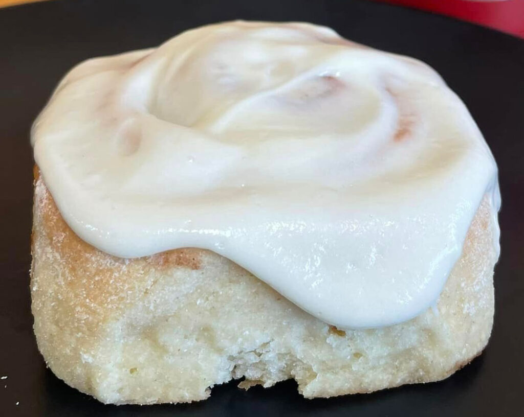 a picture of a gluten-free cinnamon roll with a rich, thick white frosting