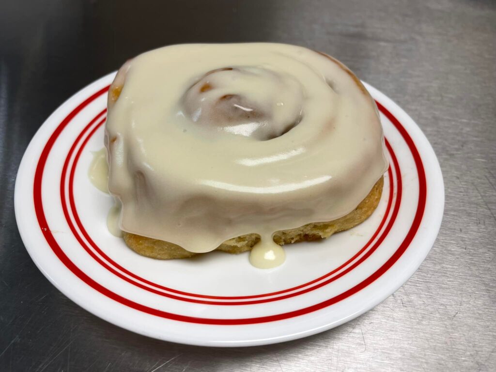 photo of dairy-free, gluten-free cinnamon roll with dairy-free frosting deliciously displayed on a plate