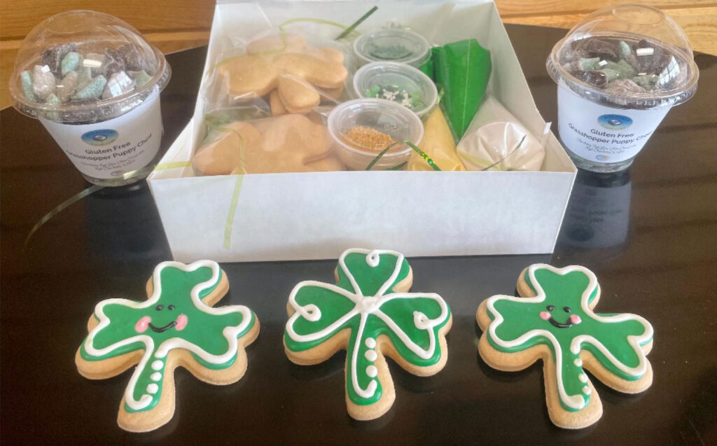 gluten-free cutout sugar cookie decorating kit for st. pathrick's day.  cookies are decorated as shamrocks,  full cookie kit  has 6 cookies, green and white frosting and two containers of sprinkles