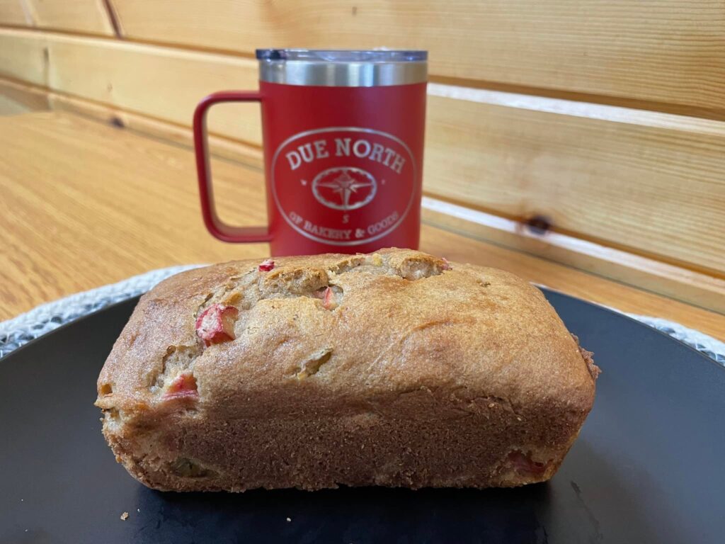 photo of loaf of rhubarb bread in front of an insulated coffee mug