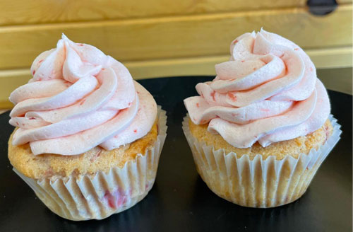 two strawberry cupcakes with strawberry frosting swirled on top